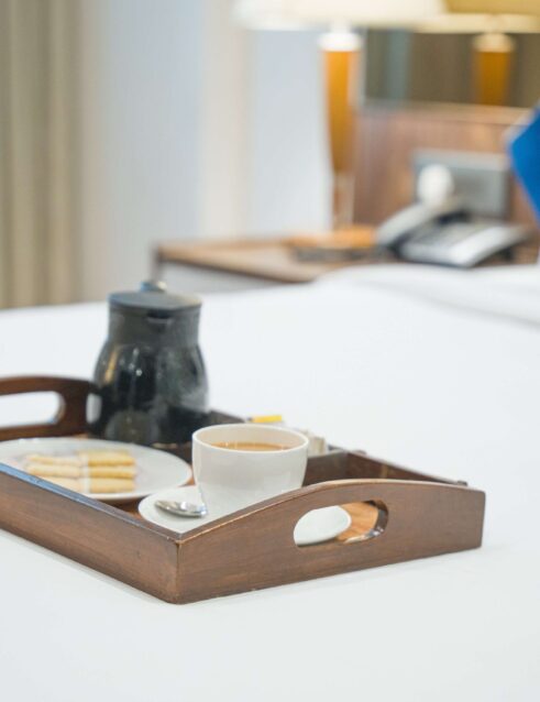 City Park Hotel room with a neatly made bed adorned with white sheets, accompanied by a cup of tea
