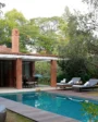 Modern luxury villa with a private swimming pool, outdoor lounge seating, and lush greenery in a peaceful setting.
